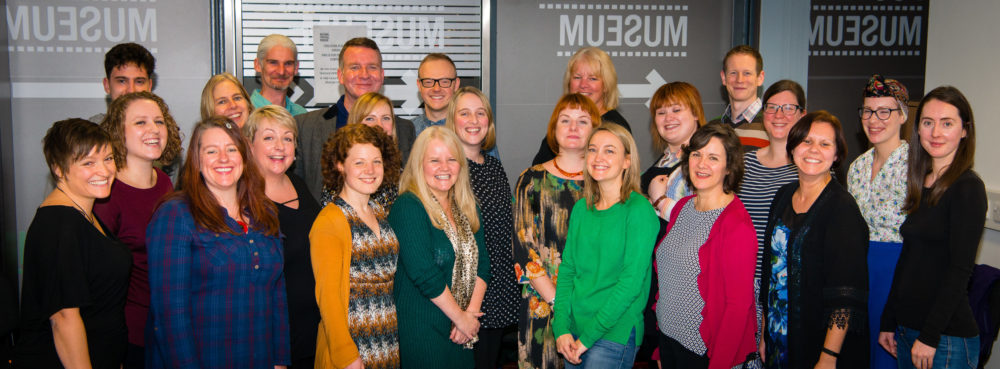 Curious Minds Team. A large group of people from a range of ages and hairstyles - predominantly women and all smiling!