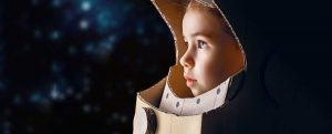 Young child in a self made astronaut helmet looking out with determined wonder at the stars.