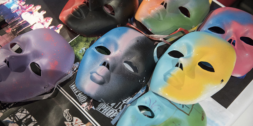 Colourful painted masks are laid out on a table