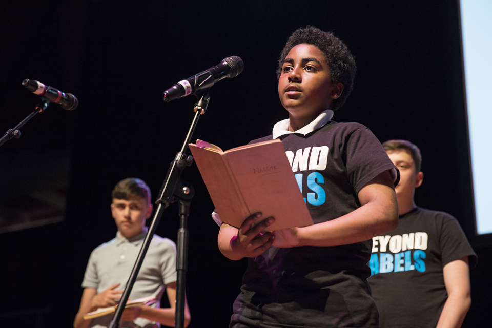 A young boy reads a poem into a microphone