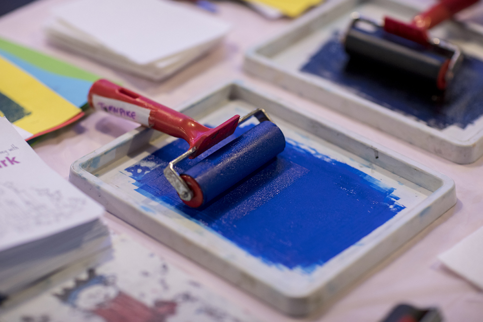 Paint roller on a table - the paint is blue and there are colours across the table.