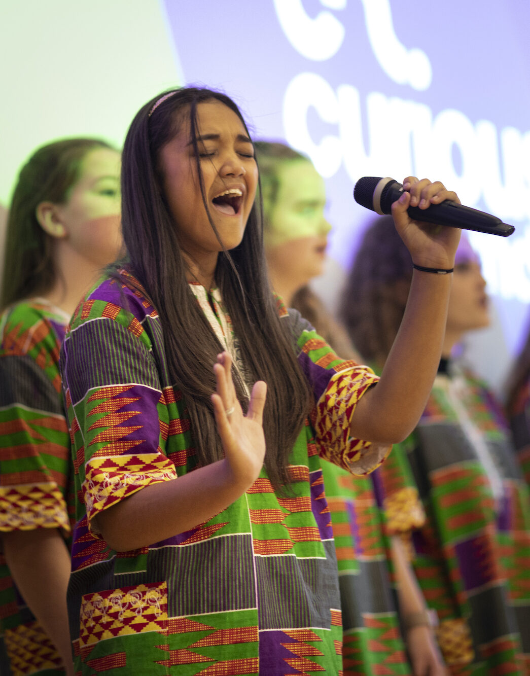 Young person holding microphone enjoys performing with other choir members