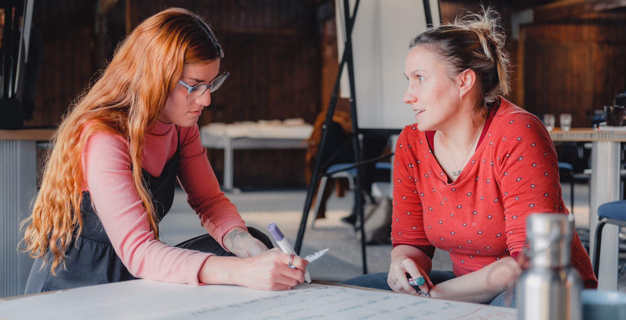 Two people are sat at a desk in discussion