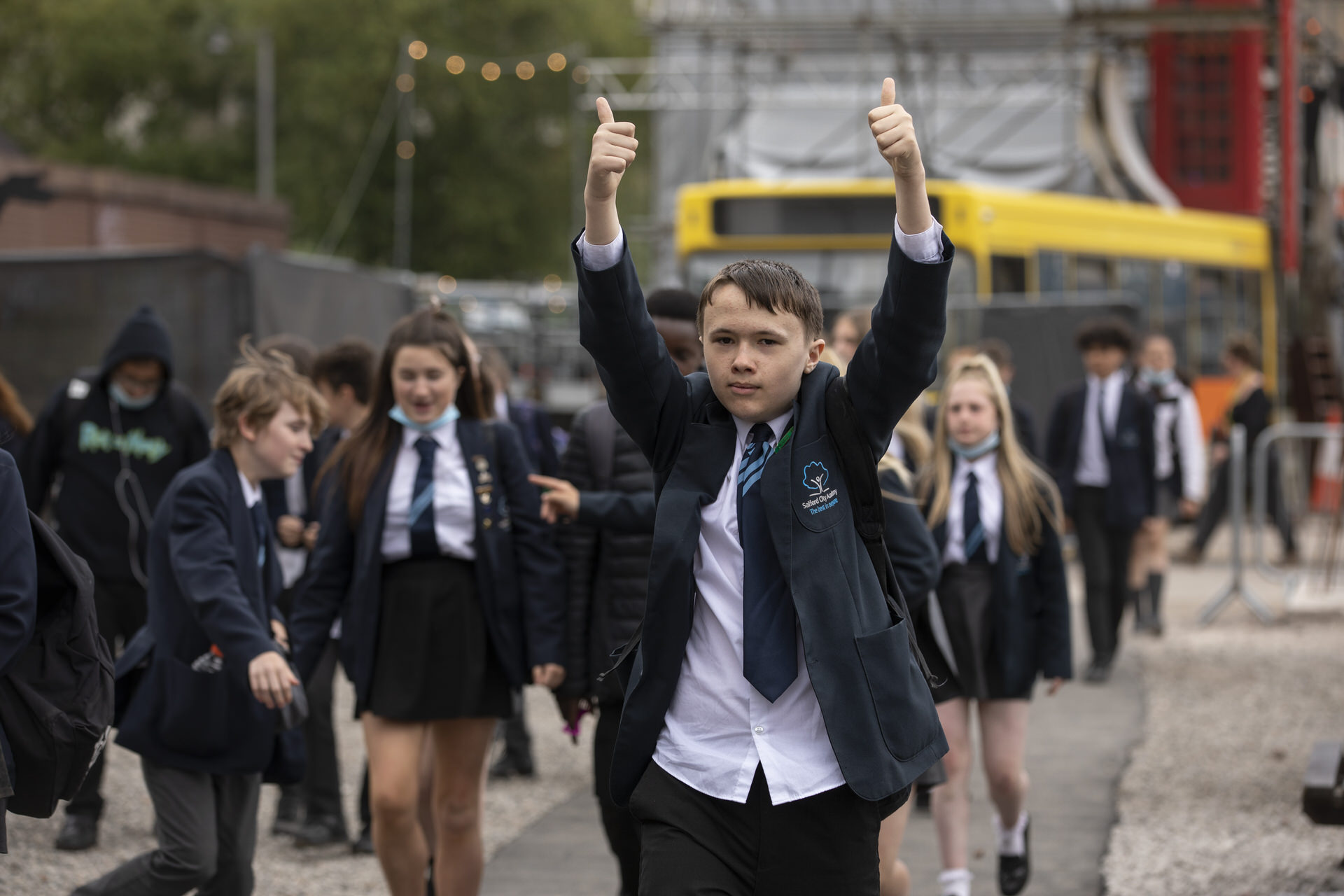 A key stage 3 school pupil on a cultural visit with both thumbs up, surrounded by other children.