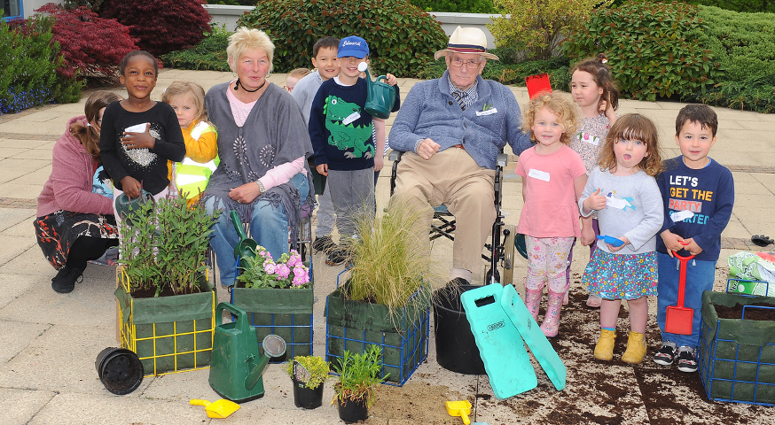A group of children and older people have been gardening together. They are happy and smiling at the camera. Image copyright: Ready Generations older adults