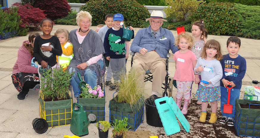 A group of children and older people have been gardening together. They are happy and smiling at the camera. Image copyright: Ready Generations older adults