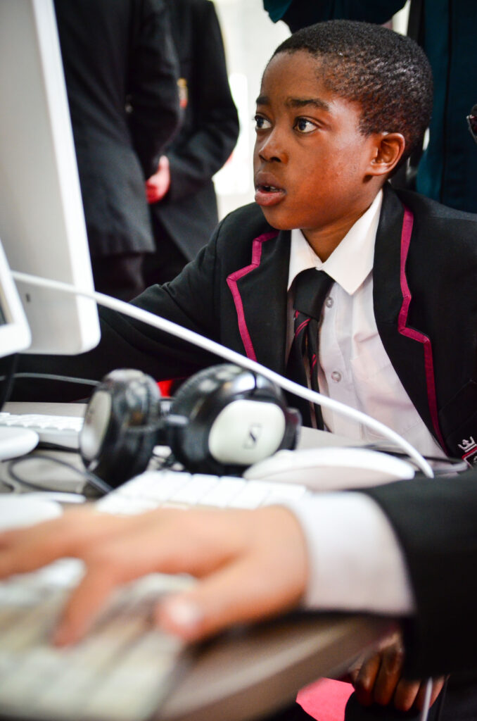 A Key Stage 3 school student in uniform works at a computer