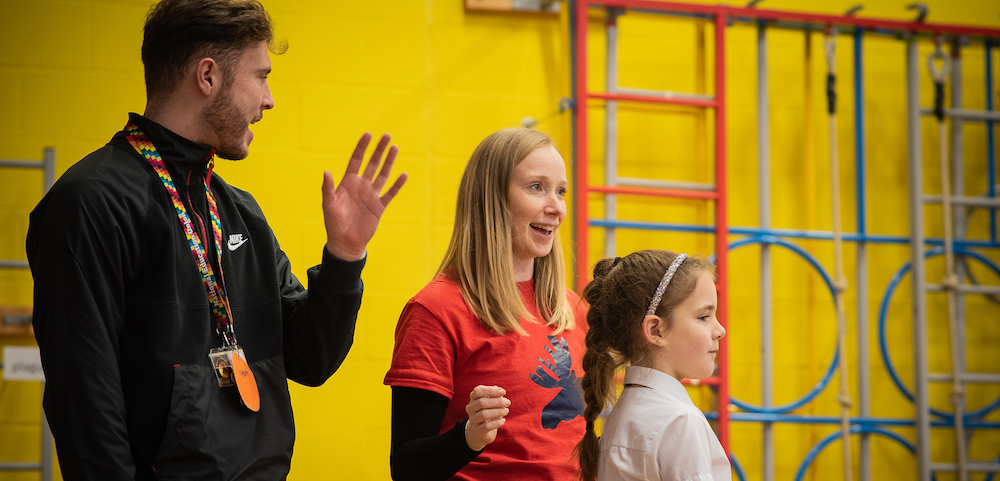 A teacher, dance artist and school pupil participate in a class together