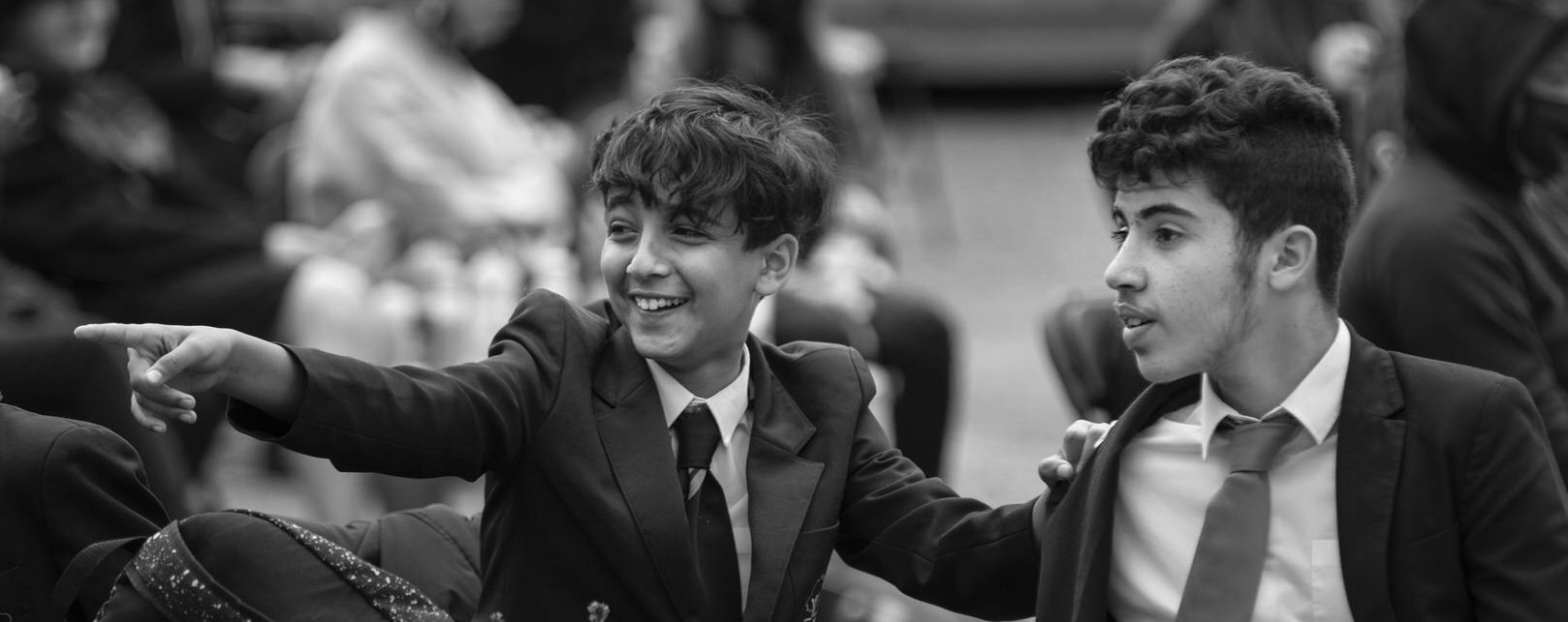 Two teenaged young people are sharing a fun and engaging experience at an cultural venue. One is pointing at something of interest out of shot. The image is in black and white