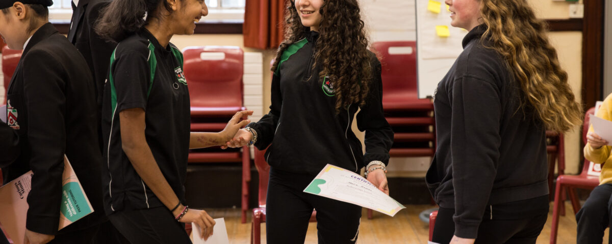 Three young people in school uniform are talking happily with each other.