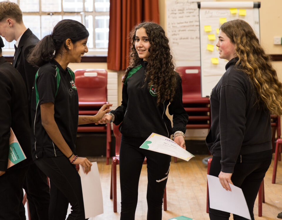 Three young people in school uniform are talking happily with each other.