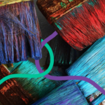 A close-up of some very colourful paint brushes with dried and wet paint still on the bristles.