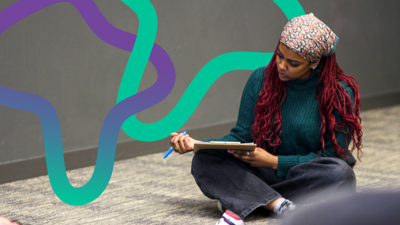 A young woman with red hair sat down making notes in a notebook. Colourful squiggles surround them.