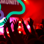 Hands in the air at a concert. Red lighting dominates as colourful squiggly lines interweave above them.