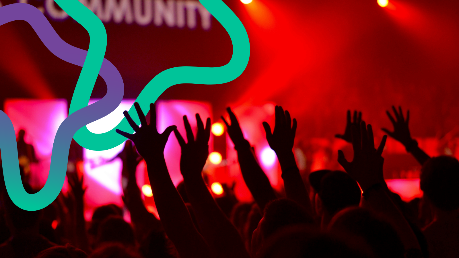 Hands in the air at a concert. Red lighting dominates as colourful squiggly lines interweave above them.